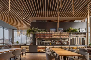 Modern restaurant interior with a large dining area, tables, chairs, and potted plants
