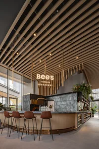 Warm and inviting restaurant interior with wooden walls and ceiling, featuring chairs, potted plants, and ample seating options