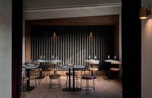 An empty restaurant with wooden tables and chairs, wine glasses on some tables, and a calm atmosphere