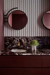 Modern bathroom with a double sink, mirror, and elegant decor, featuring vases and well-lit design