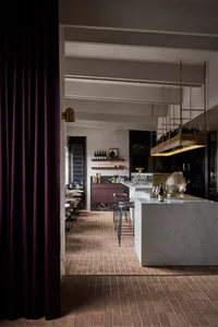 Elegant restaurant interior with marble countertops, a wine rack, and wooden accents, featuring a comfortable dining area and kitchenette
