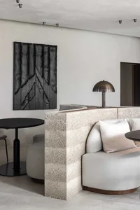 A modern living area with two couches, a dining table, and chairs arranged in a comfortable manner, featuring white walls and wooden furniture