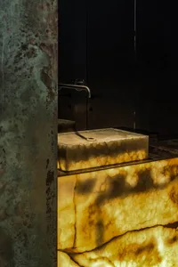 A vintage bathroom with a marble sink, a toilet, and a worn-down appearance