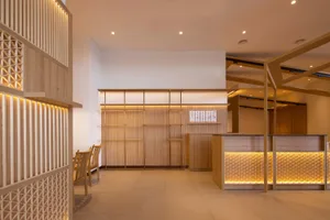 Open living area with wooden floors and walls, featuring chairs and a warm atmosphere