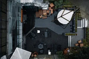 A modern restaurant space with black furniture, umbrellas, and a mix of seating areas