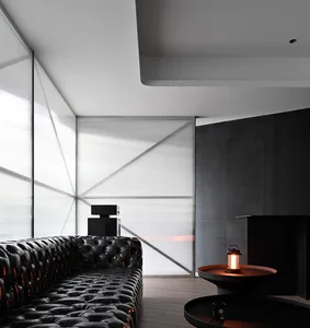 Modern living room with black leather couches, white panel walls, and a fireplace, featuring a clean and minimalist aesthetic