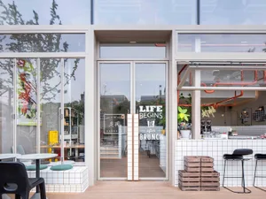 Inviting restaurant space with a wooden floor, chairs, and a potted plant, perfect for dining or coffee