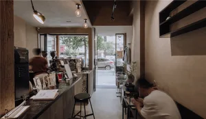 Inviting coffee shop interior with a counter, chairs, and decorative elements, featuring wooden accents and a warm atmosphere