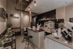 A clean and organized restaurant kitchen with a counter, chairs, and wood elements, suggesting a space for food and drink service