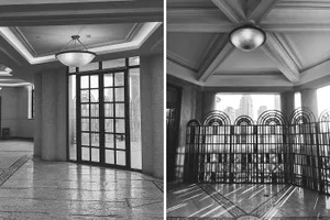 A modern lobby with concrete floors and walls, featuring large windows for natural light and a door connecting to a smaller, more confined space
