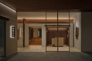 Open modern living area with two couches, a chair, and a glass door leading to another room, well-lit and comfortable