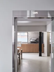 A modern cafe with wood paneling, glass door, and tables and chairs, well-lit and inviting