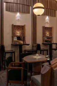 A warm and inviting restaurant interior with multiple dining tables and chairs, featuring a mix of wood and metal elements