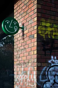 Exterior photo of a brick building with graffiti on its side, taken during the daytime