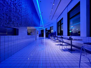 A calm and inviting restaurant with a blue tiled floor and walls, featuring scattered chairs and dining tables