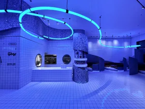 A modern building with a large, brightly lit interior featuring white tile walls, round mirrors, and a contemporary design