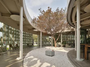 A spacious indoor area with a circular design, featuring a dining table, chairs, and a potted plant, creating an inviting atmosphere for gatherings