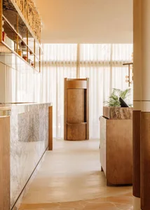 Warm and inviting restaurant interior with wooden floors and walls, natural light, and decorative bottles