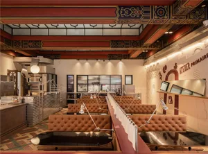 A long dining area with multiple tables and chairs, benches along the walls, and an inviting atmosphere for socializing and meals
