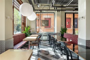 Dining area with multiple tables and chairs, wood elements, and natural light