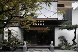 A serene Asian-style building with a stone archway entrance, dimly lit interior, and two statues near the doorway