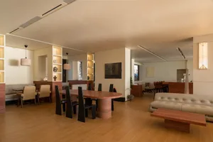 Open concept living area with two couches, a wooden dining table, and hardwood flooring, featuring a vase on the table and a modern, well-organized design