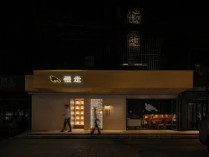 A warm and inviting Asian restaurant at night with a prominent fish sign, chairs, and a cozy dining area