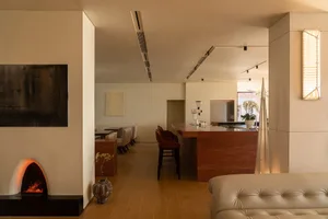 Open living area with wooden floors and walls, featuring a combined kitchen, dining, and living space with multiple seating areas and decorative elements
