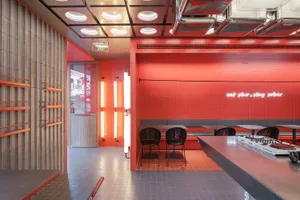 Cozy restaurant dining space with red brick walls, orange accents, and multiple seating options including chairs and benches