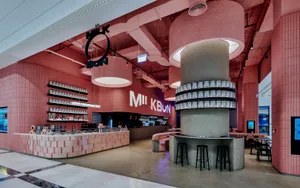 A restaurant bar area with stools, a counter, and bottles, set in a warm and inviting atmosphere with wooden accents