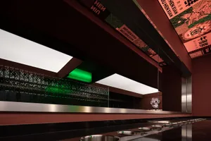 A modern bar area with a metal counter, several bowls, and bottles, set in a well-lit environment