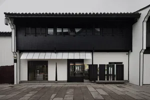 Old building with a black exterior, white roof, and large window, featuring a glass door and traditional architectural style