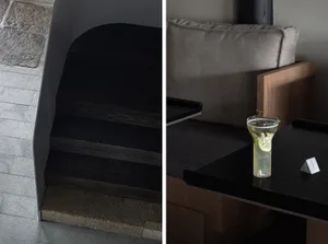Modern living space with a staircase, a couch, a dining table, and bottles on surfaces