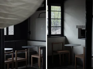 Dimly lit dining area with two tables and wooden chairs, creating a warm and inviting atmosphere