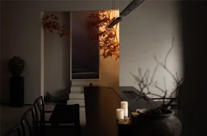 A kitchen with a black countertop, wooden dining table, and two chairs, accompanied by candles and a potted plant