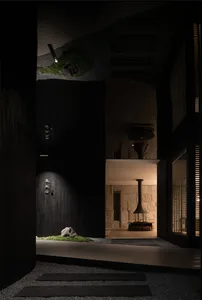 A narrow dark hallway with a fireplace, two doors, and a black doorway leading to a hallway