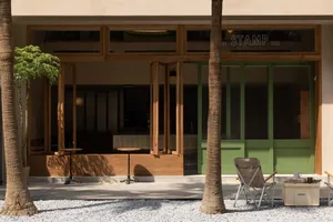 A relaxed outdoor dining area with a green door, palm tree, and a few chairs and a table