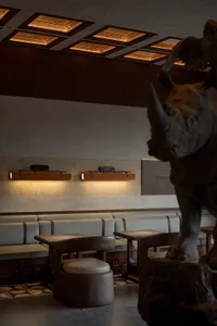 A restaurant interior with a large rhinoceros statue as its centerpiece, surrounded by multiple chairs in an elegant and inviting atmosphere