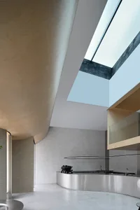 Modern kitchen and living area with white walls, wooden floors, and natural light from skylights