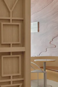 A modern dining space with wooden walls, two dining tables, and a bench, creating a warm and inviting atmosphere
