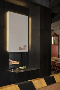 A casual Asian restaurant with a woman preparing food behind a counter, surrounded by chairs and a bowl on the counter