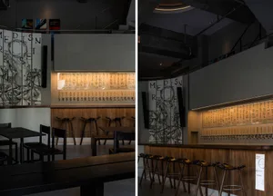 Industrial-style bar with exposed brick walls, wooden accents, and a long row of beer taps, offering a cozy and inviting atmosphere with ample seating options