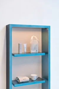 A clean and organized bathroom with a blue shelf holding two bottles of lotion and two bags, adding a pop of color to the neutral space
