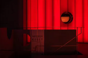 A futuristic interior space with a red lit wall, two round decorative elements, and a striking visual impact from vibrant colors and intriguing shapes