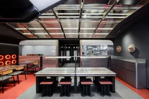 Industrial kitchen with metal tables, black chairs, and commercial appliances, creating a functional and stylish space for events or gatherings