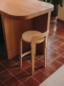 A minimalist dining space with a wooden table and chair, set against a tiled floor
