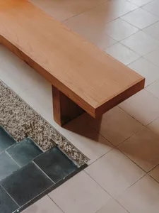 A calm and inviting room with a wooden bench on a tile floor, featuring a simple design and a patterned tile layout