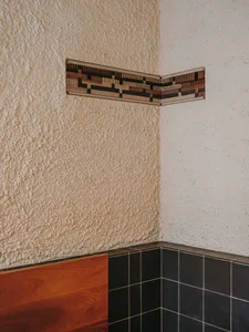 a wooden bench in front of a black and white tiled backsplash in a modern and stylish interior design
