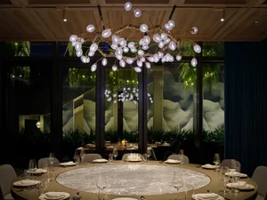 A sophisticated dining space with a large glass table surrounded by chairs, wine glasses, and cups, set in a well-lit room