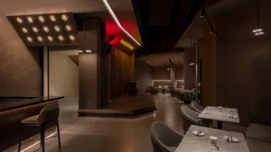 A restaurant interior with gray and red tones, featuring chairs, couches, and dining tables in a warm and inviting atmosphere